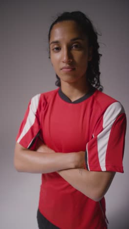 Vertical-Video-Studio-Portrait-Of-Female-Footballer-Wearing-Club-Kit-Against-Grey-Background